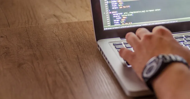 Close-up of a person coding on a laptop, showcasing web development and programming concepts.