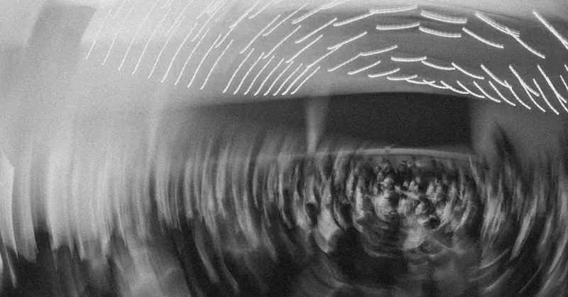 Abstract motion blur of a crowd under dynamic light trails in black and white.