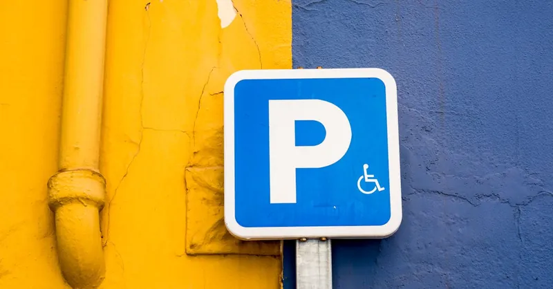 A blue parking sign against vibrant yellow and blue walls, symbolizing accessibility.