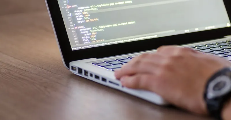 Person coding on a laptop with HTML code on screen, showcasing development work.