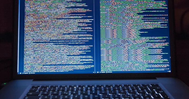 Laptop displaying source code with dual screens for software development.